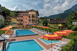 Un resort con varias piscinas, tumbonas y sombrillas.