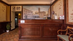 A reception desk with a mural of a historic town square, a clock, and a sign indicating a local area. - Hotel Trastevere (Rome)
