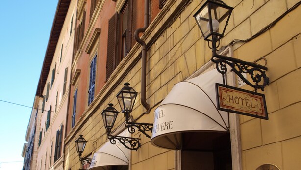 A row of hotel signs with traditional lantern-style lighting, indicating a historic or classic building facade. - Hotel Trastevere (Rome)