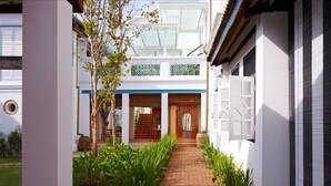 A traditional building with a central wooden door, a brick pathway, and a garden area with plants. - 23 LoveLane Penang (George Town)