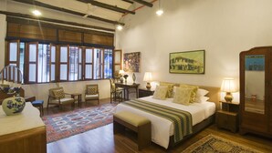 A bedroom with a large bed, two bedside tables with lamps, a desk with a chair, a window with blinds, and a painting on the wall. - 23 LoveLane Penang (George Town)