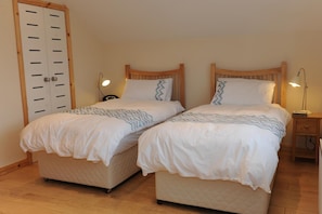 Habitación doble con dos camas, cada una con cabecera, mesitas de noche y lámparas.