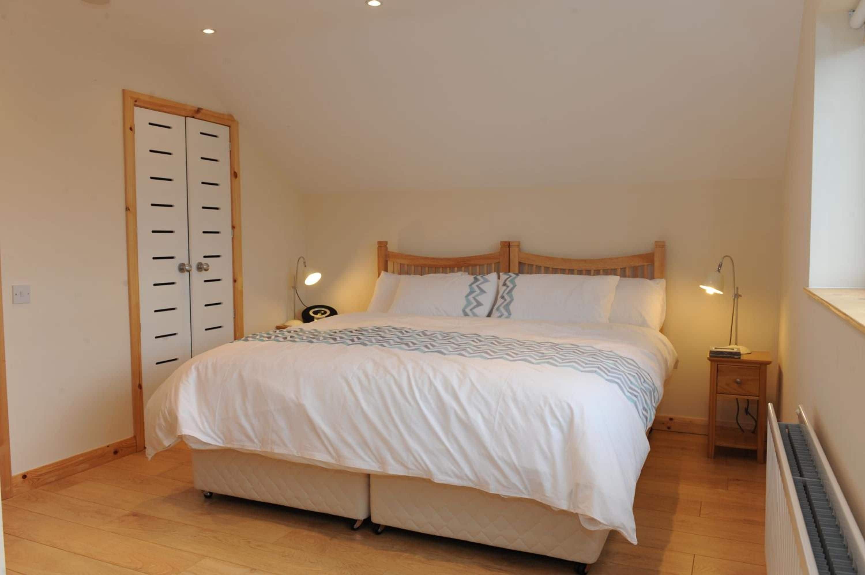 A bedroom with a bed, bedside lamps, a wooden door, and a radiator.