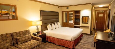 Una habitación de hotel con una cama grande, un sofá, un escritorio y un espejo.