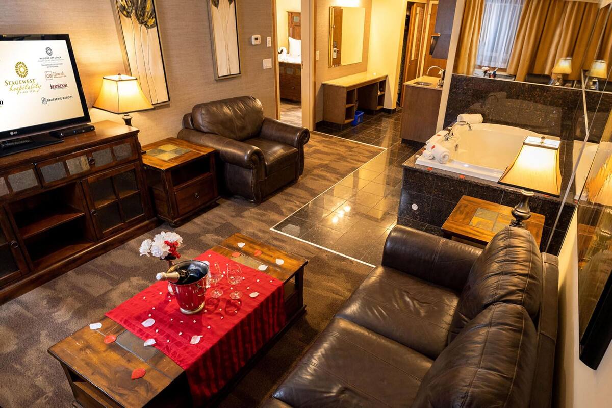 A hotel room with a living area, a separate bathroom, and a dining table with a red tablecloth.