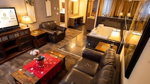 A hotel room with a living area, a separate bathroom, and a dining table with a red tablecloth. - Best Western Plus Rose Country Hotel (Camrose)