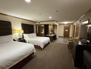 A hotel room with two beds, a desk, a television, and a wardrobe.