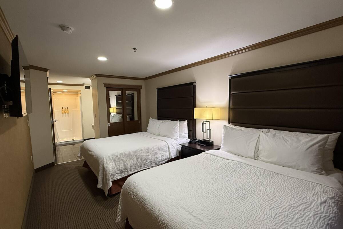 A hotel room with two beds, a wardrobe, a bathroom, and a TV.