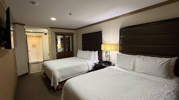 A hotel room with two beds, a wardrobe, a bathroom, and a TV.
