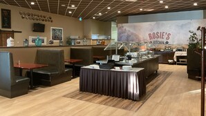 A restaurant interior with booths, a buffet area, and a kitchen in the background. - Best Western Plus Rose Country Hotel (Camrose)