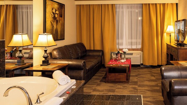 A hotel room with a large bed, a sofa, a coffee table, and a TV. - Best Western Plus Rose Country Hotel (Camrose)