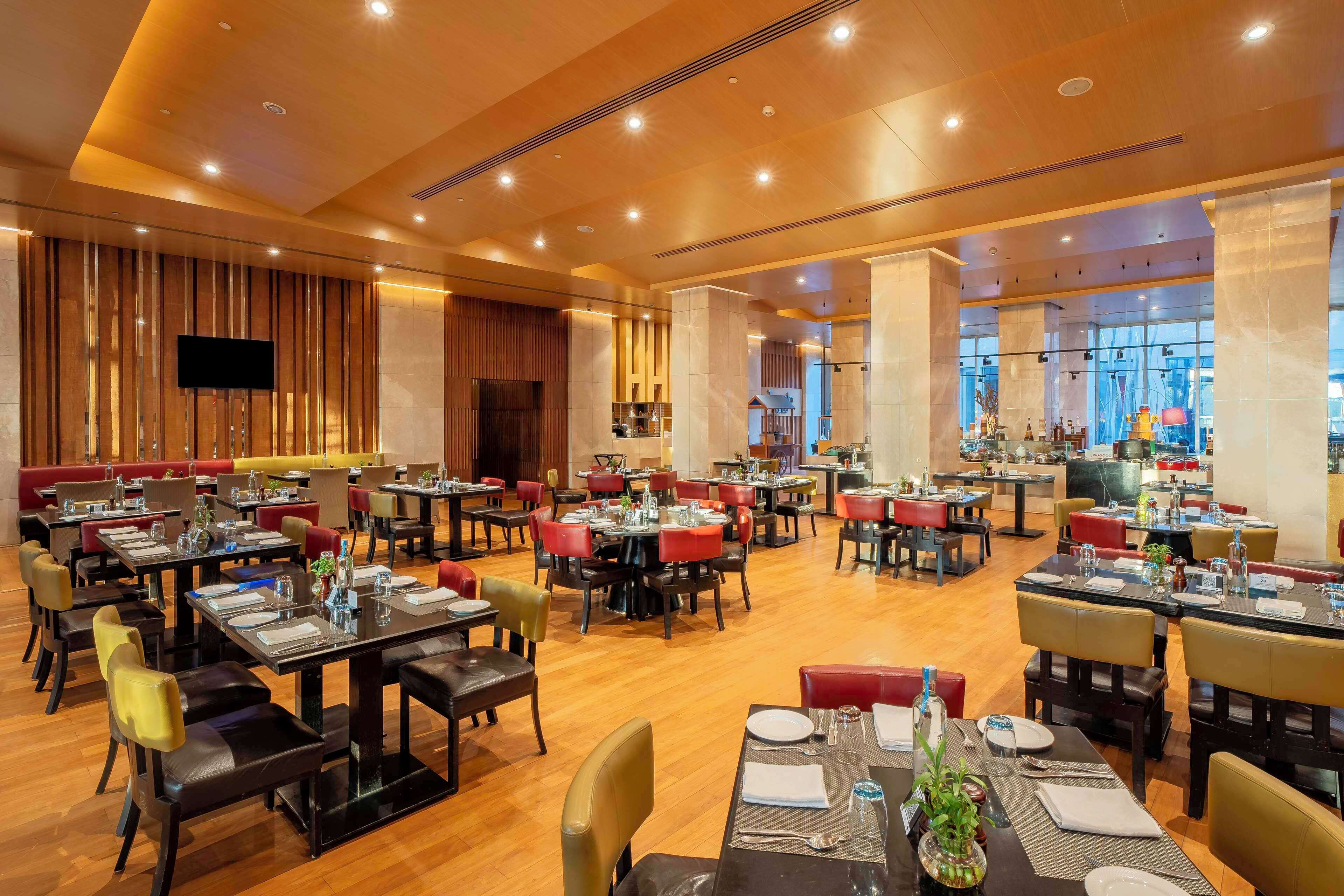 A spacious restaurant with multiple dining areas, wooden flooring, and a modern interior design.