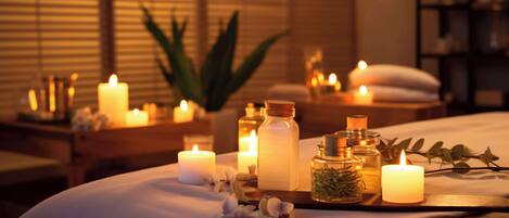 Un dormitorio con cama, velas y diversos artículos de tocador sobre una mesita de noche.