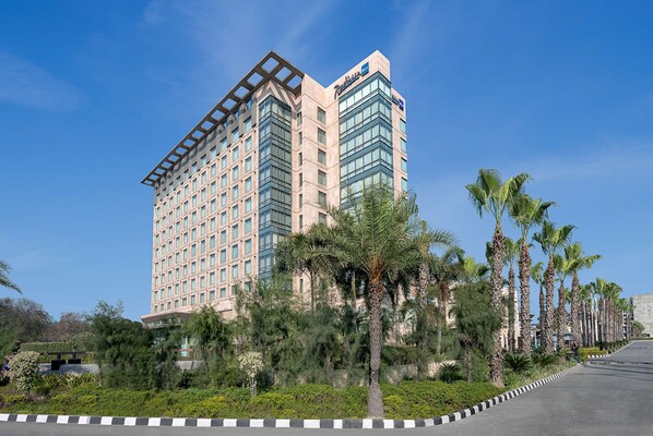 A high-rise hotel with a modern design, featuring a prominent glass facade and a rooftop terrace. - Radisson Blu Hotel Amritsar (Amritsar)