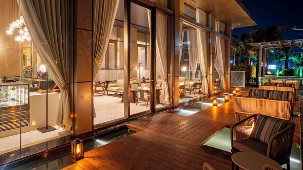 A modern outdoor lounge area with wooden flooring, cushioned seating, and ambient lighting. - Radisson Blu Hotel Amritsar (Amritsar)