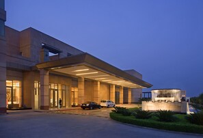 A modern hotel entrance with a covered driveway, a reception desk, and a landscaped garden area. - Radisson Blu Hotel Amritsar (Amritsar)