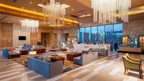 A spacious lobby with modern furniture, large chandeliers, and a view of the cityscape through large windows. - Radisson Blu Hotel Amritsar (Amritsar)