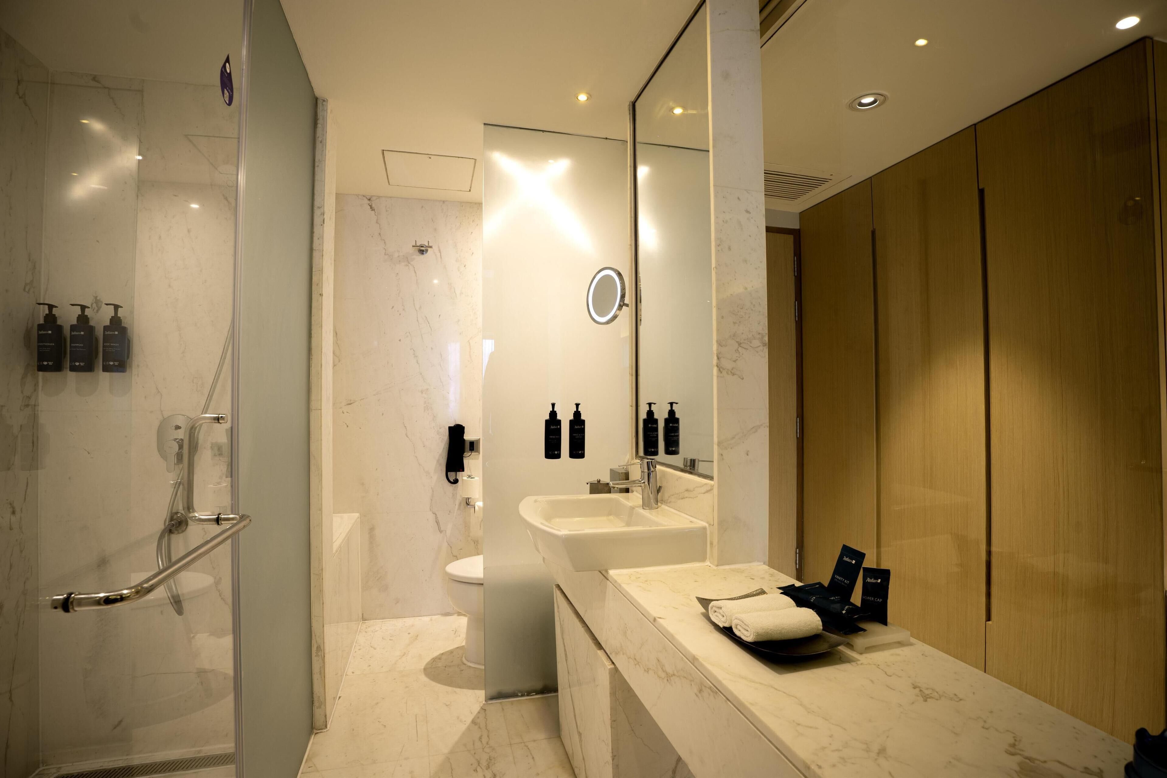 A modern bathroom with a glass shower enclosure, a vanity with a sink and mirror, and a toilet.