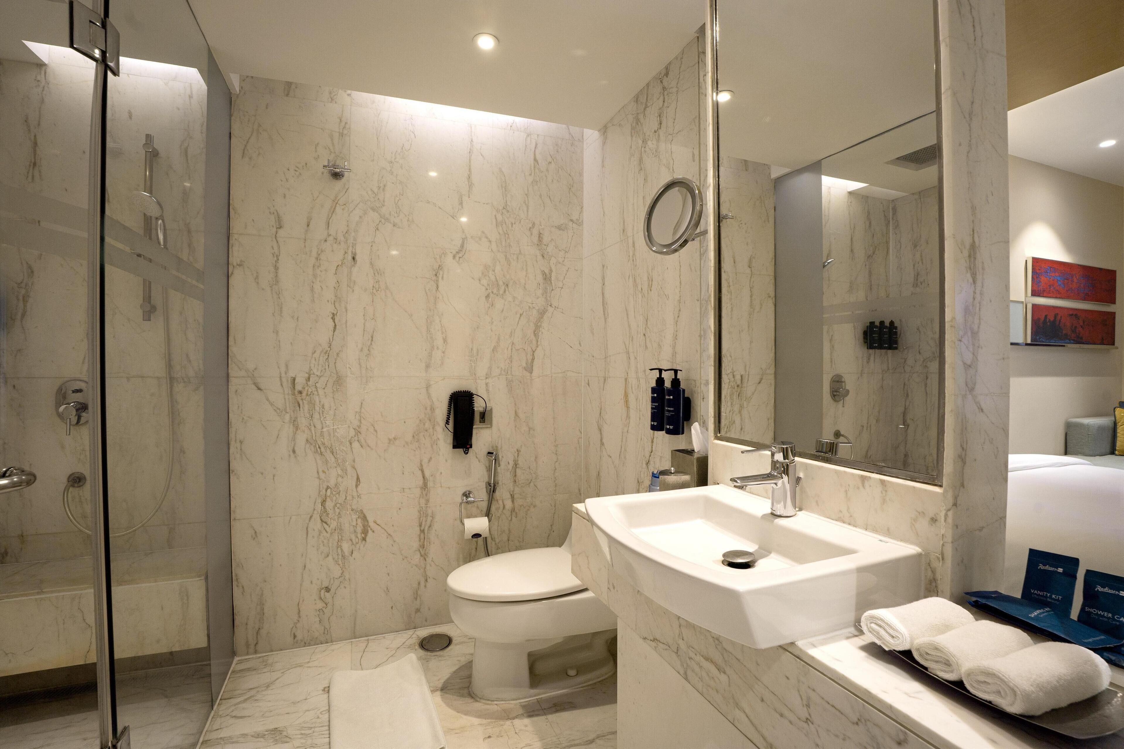 A modern bathroom with a glass shower enclosure, a white toilet, and a large sink with a mirror.