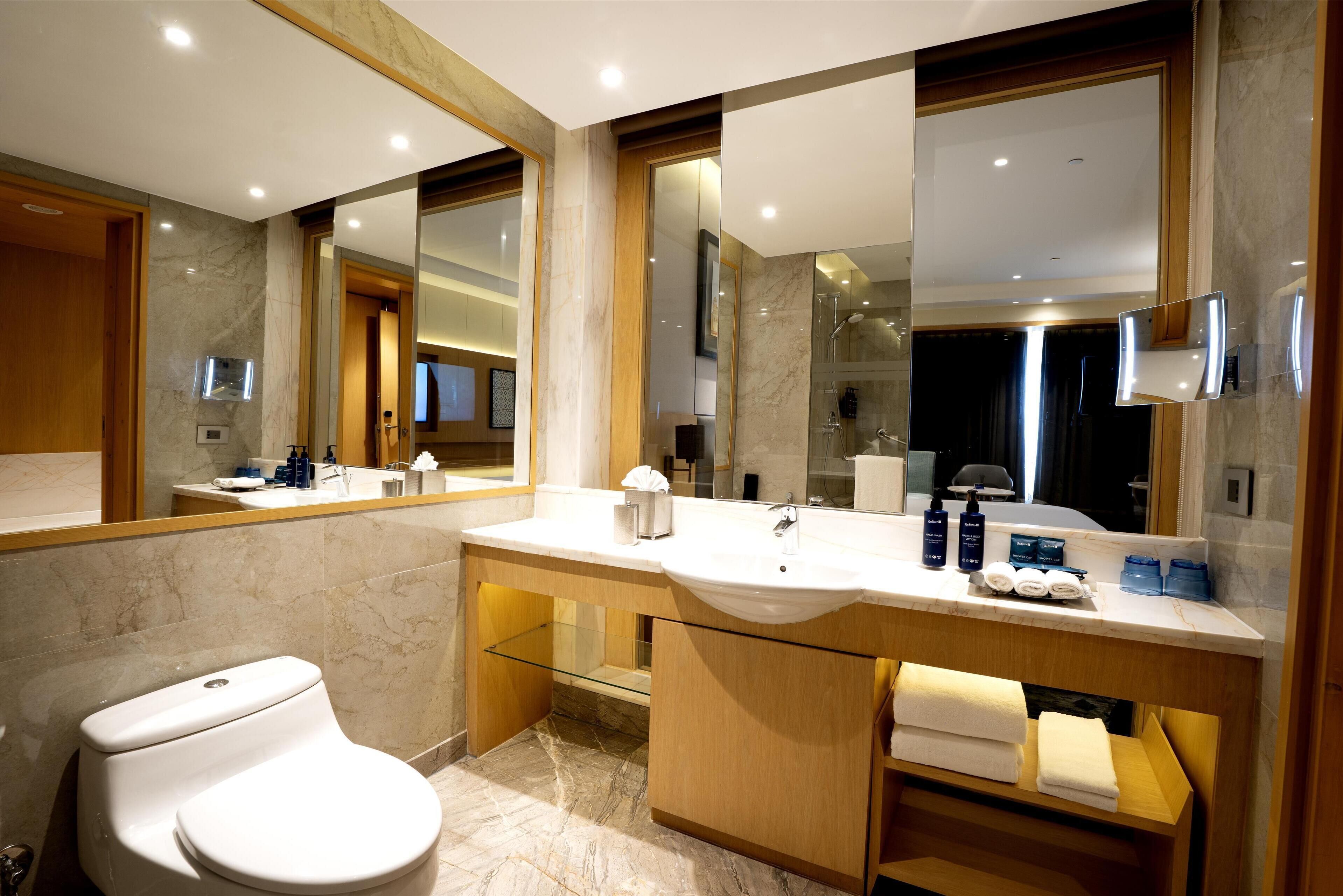 A modern bathroom with a large mirror, a sink, and a toilet.