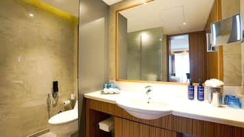 Une salle de bain moderne avec un mur en marbre, un grand miroir et un meuble-lavabo en bois.