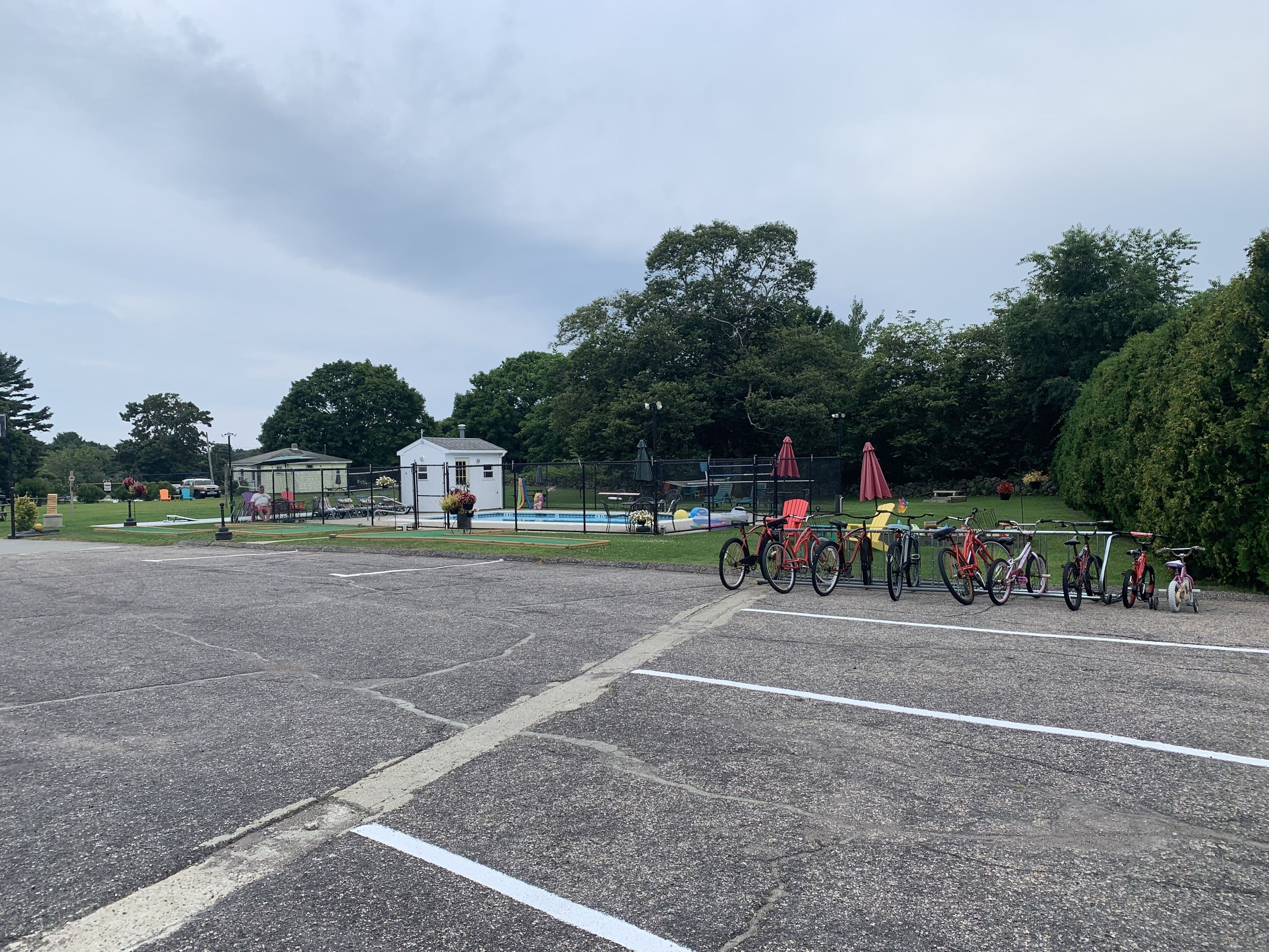 A parking lot with bicycles and a small building in the background.
