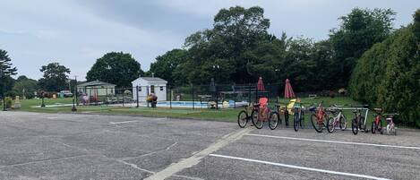 A parking lot with bicycles and a small building in the background.