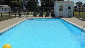 Une piscine rectangulaire, avec un pavillon blanc en arrière-plan.