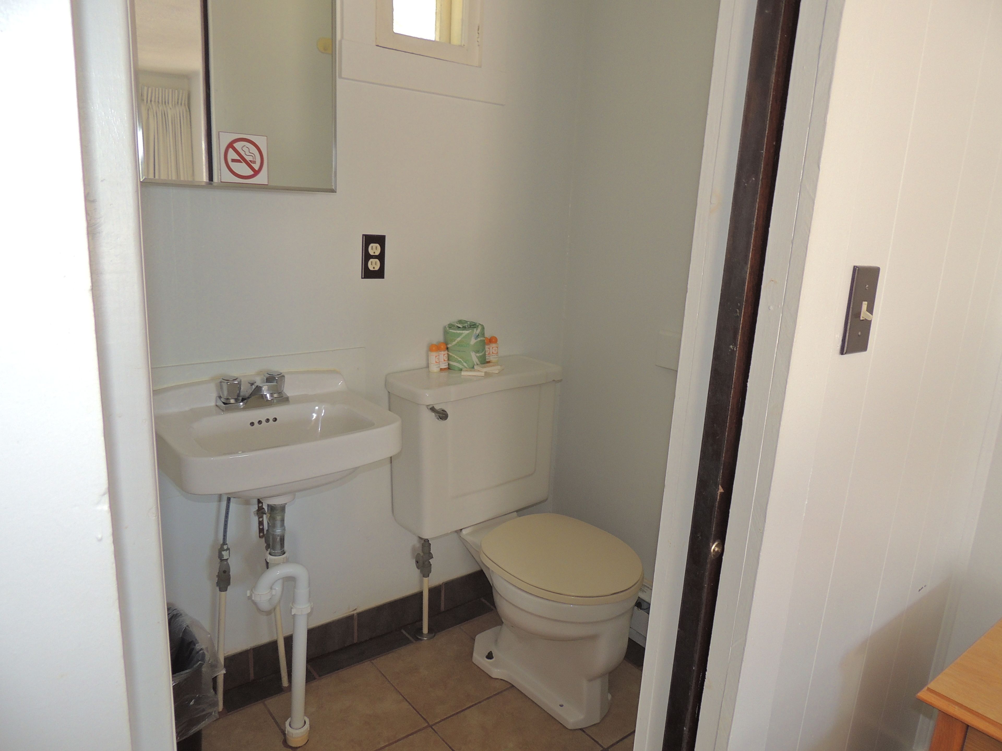 A small, clean bathroom with a white sink, toilet, and a mirror above the sink.