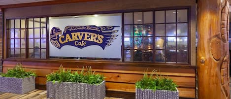 A Carver's Café interior with wooden benches, potted plants, and a large sign.
