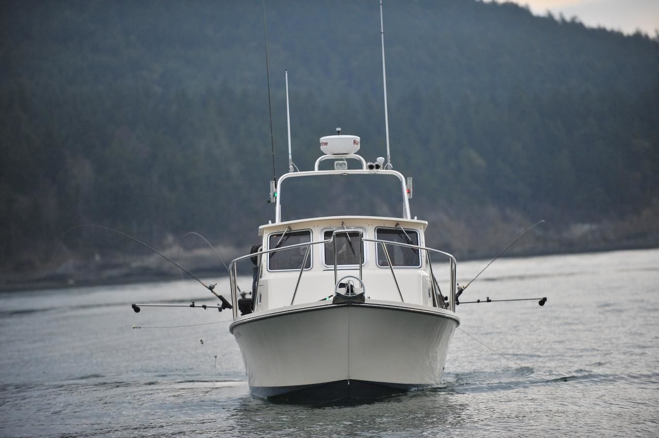 A boat with a cabin and fishing rods on the water.