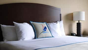 A neatly made bed with white linens and a decorative pillow featuring a blue and red design.
