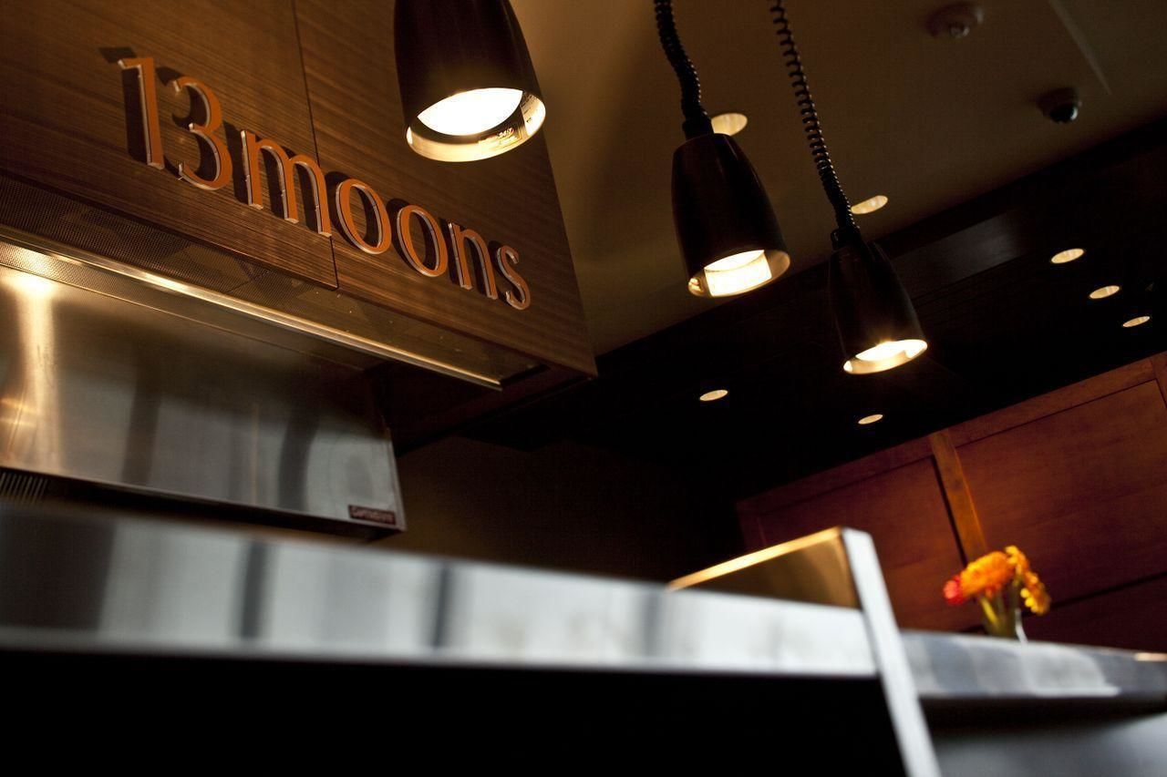 A restaurant interior with a sign reading "13moons" and pendant lighting.