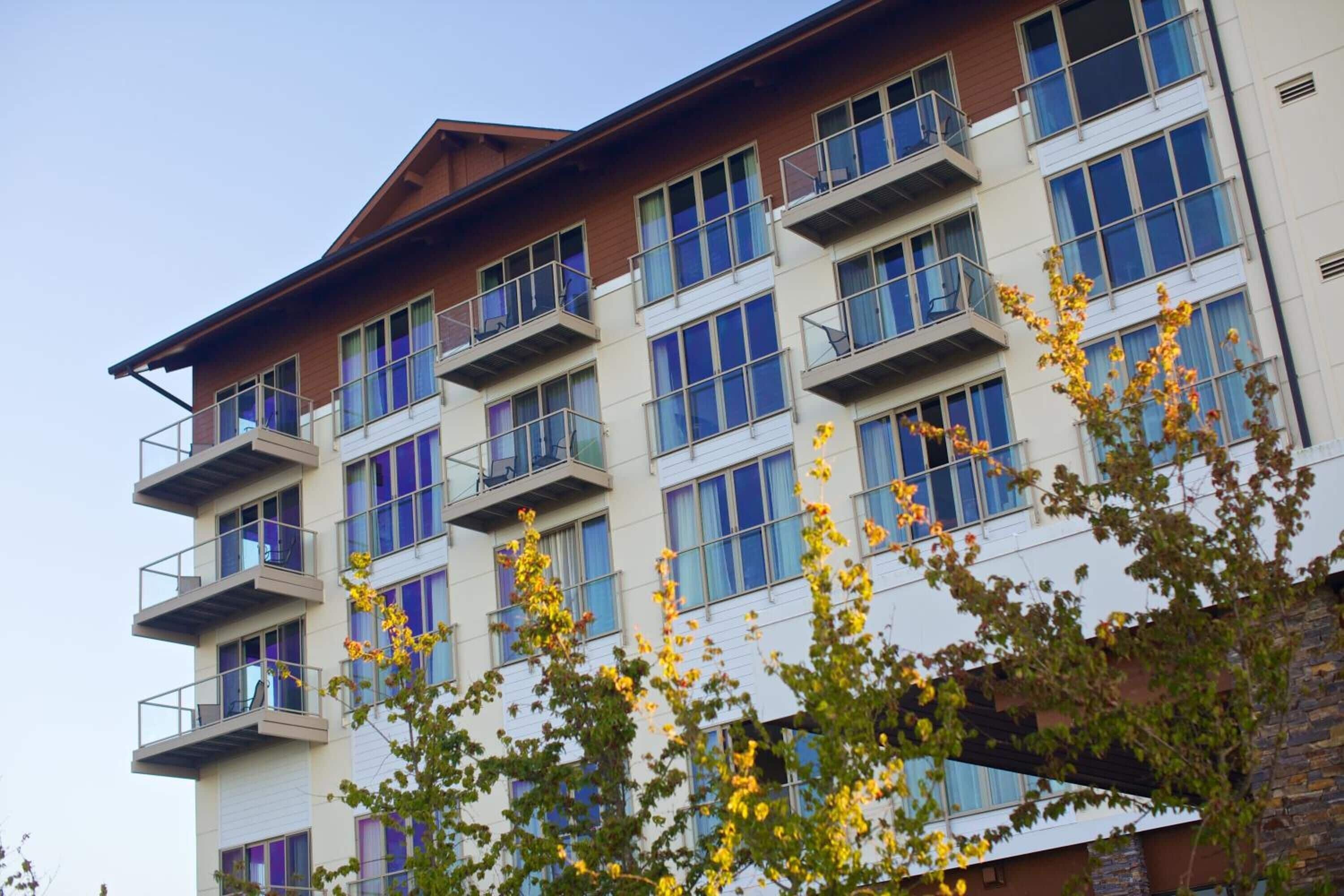 Un edificio de varios pisos con balcones y grandes ventanales.
