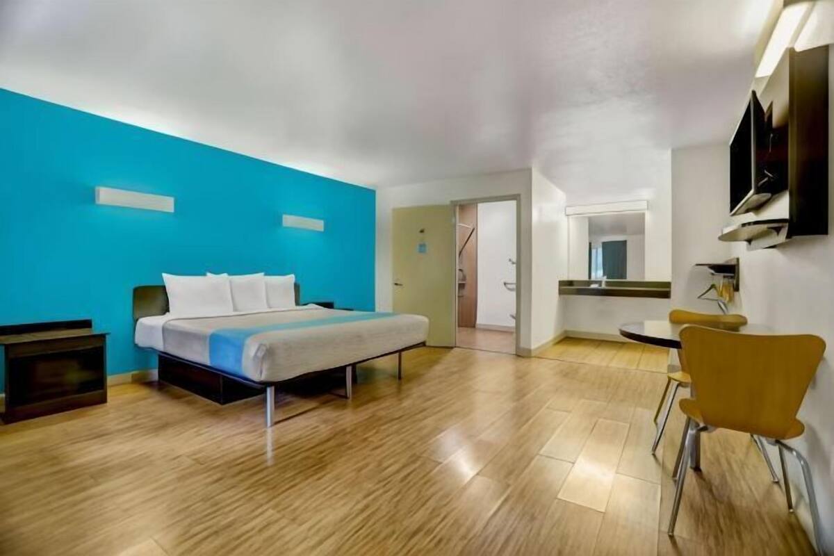 A room with a bed, a chair, a desk, and a mirror.