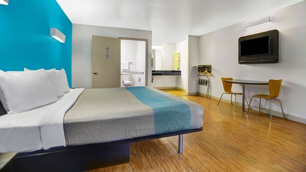 A hotel room with a bed, a desk, and a TV.