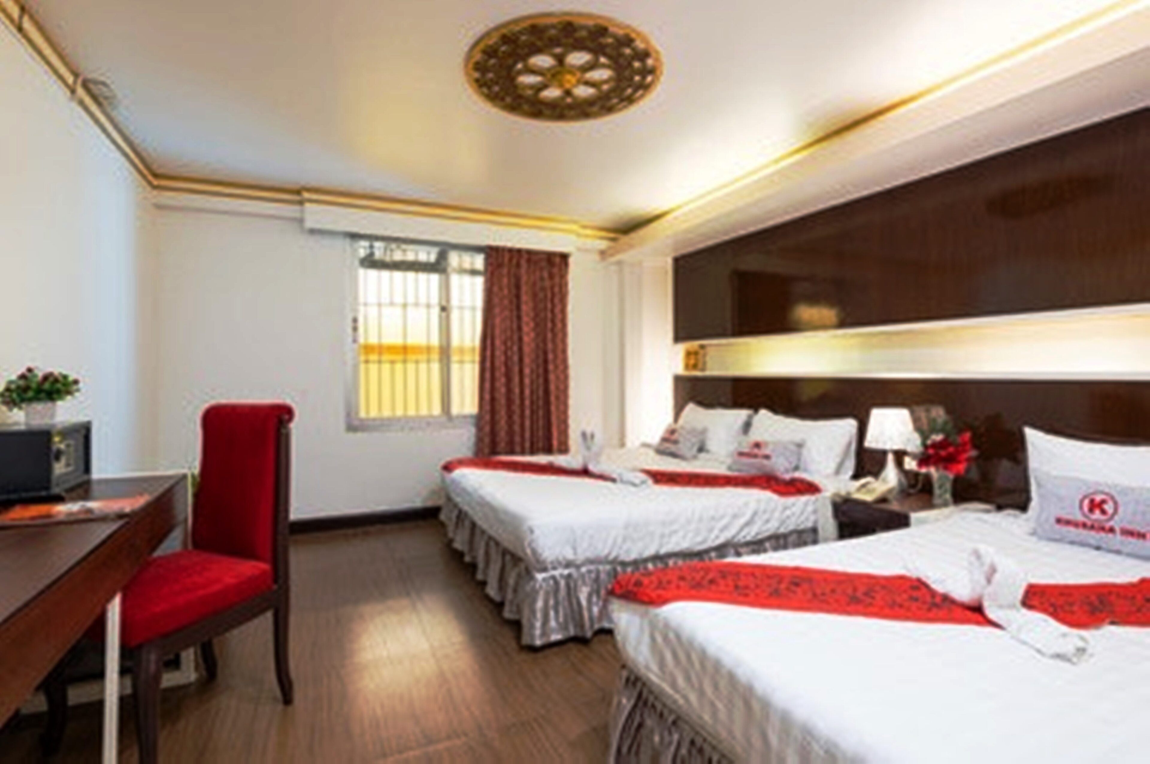 A hotel room with two beds, a desk, and a chair.