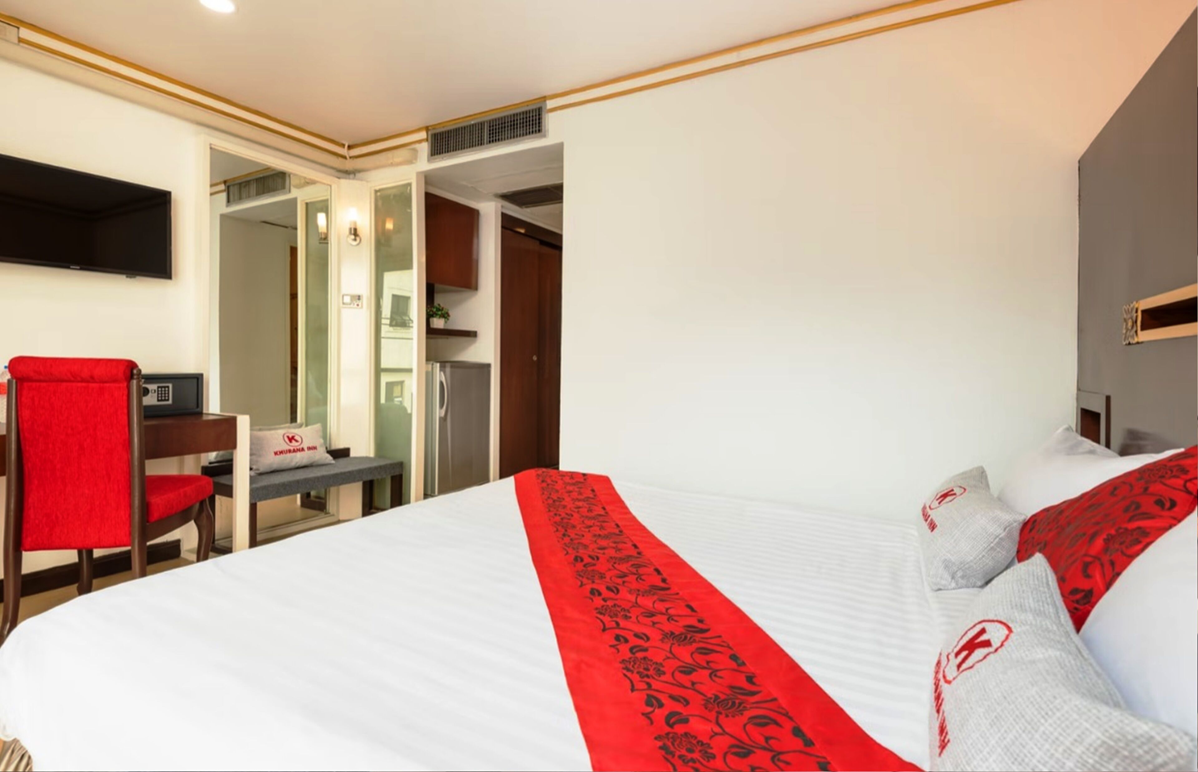 A hotel room with a bed, a desk, a chair, and a TV.