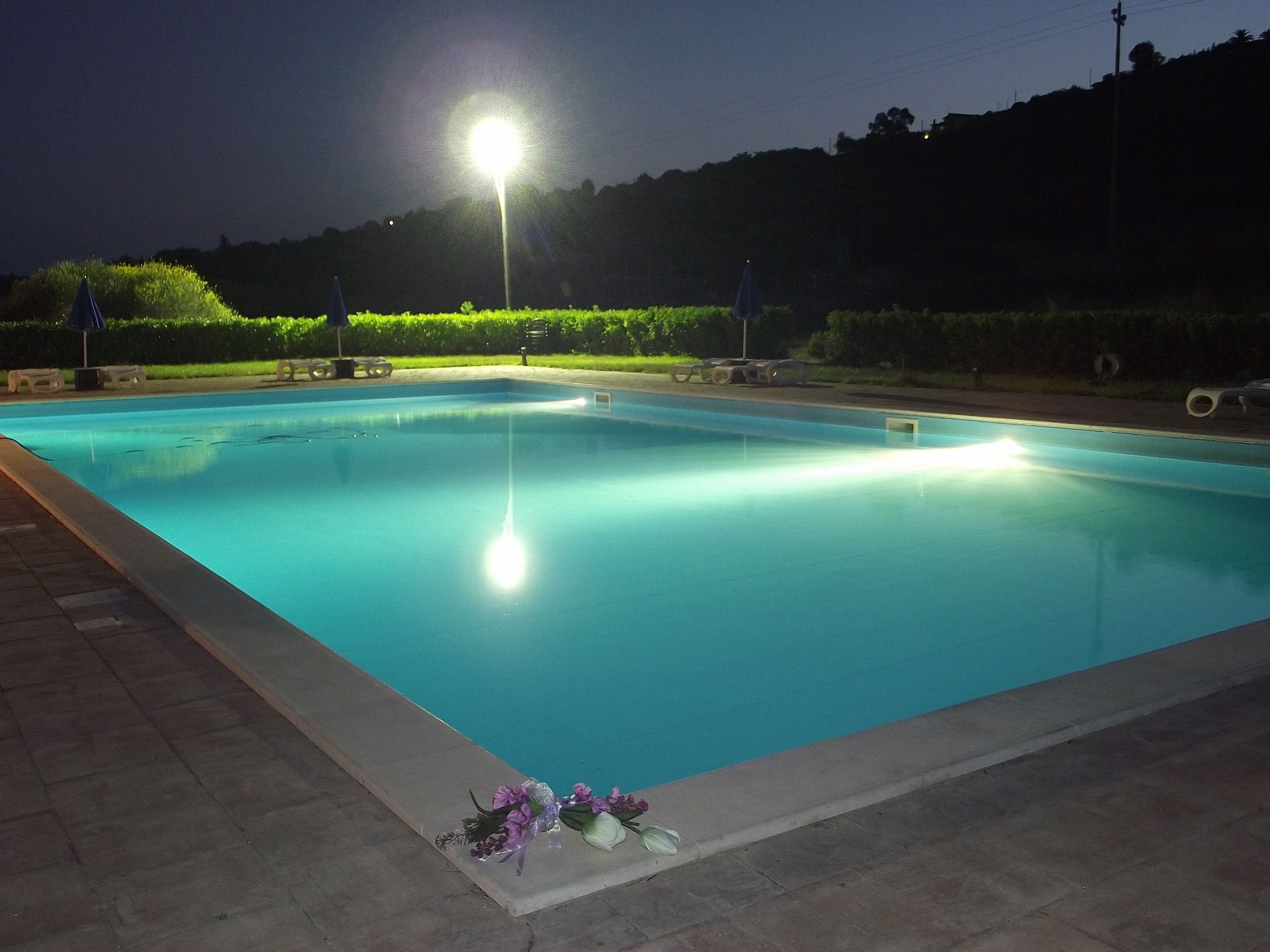 A swimming pool at night with a light source above it.