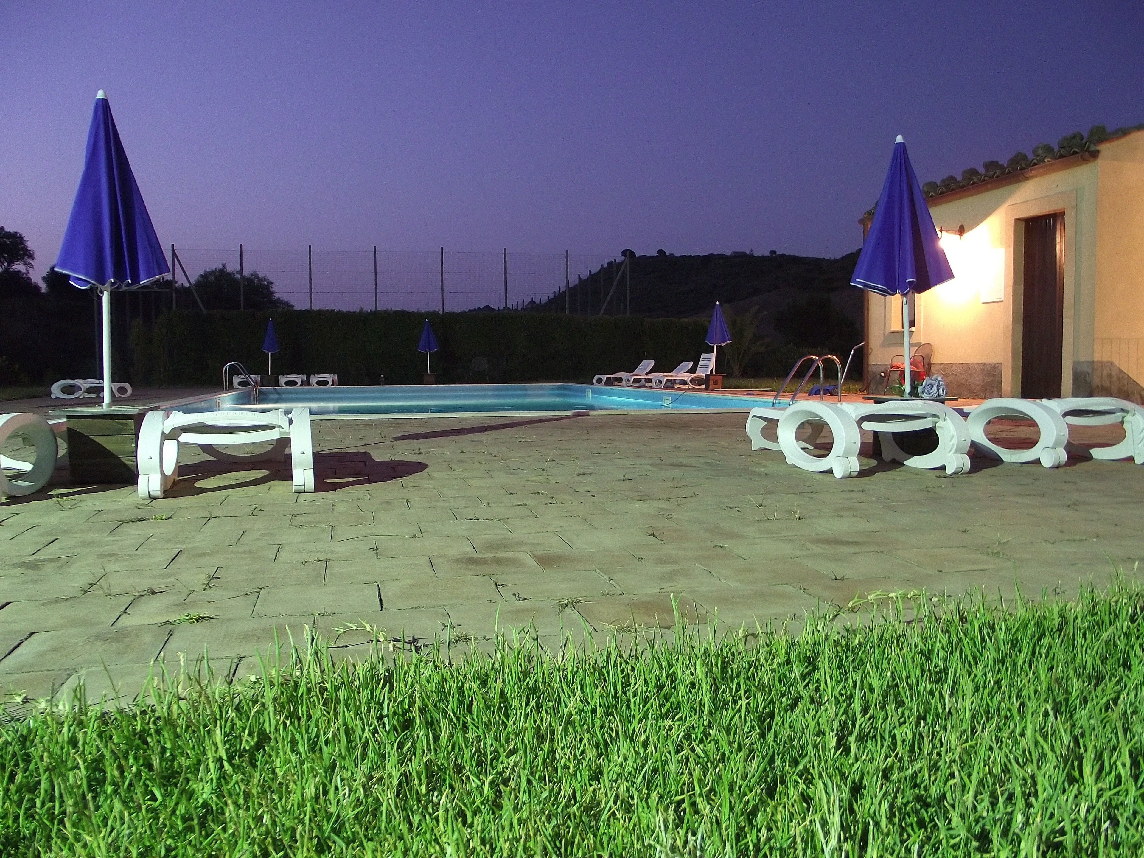 An outdoor swimming pool area with lounge chairs and umbrellas.