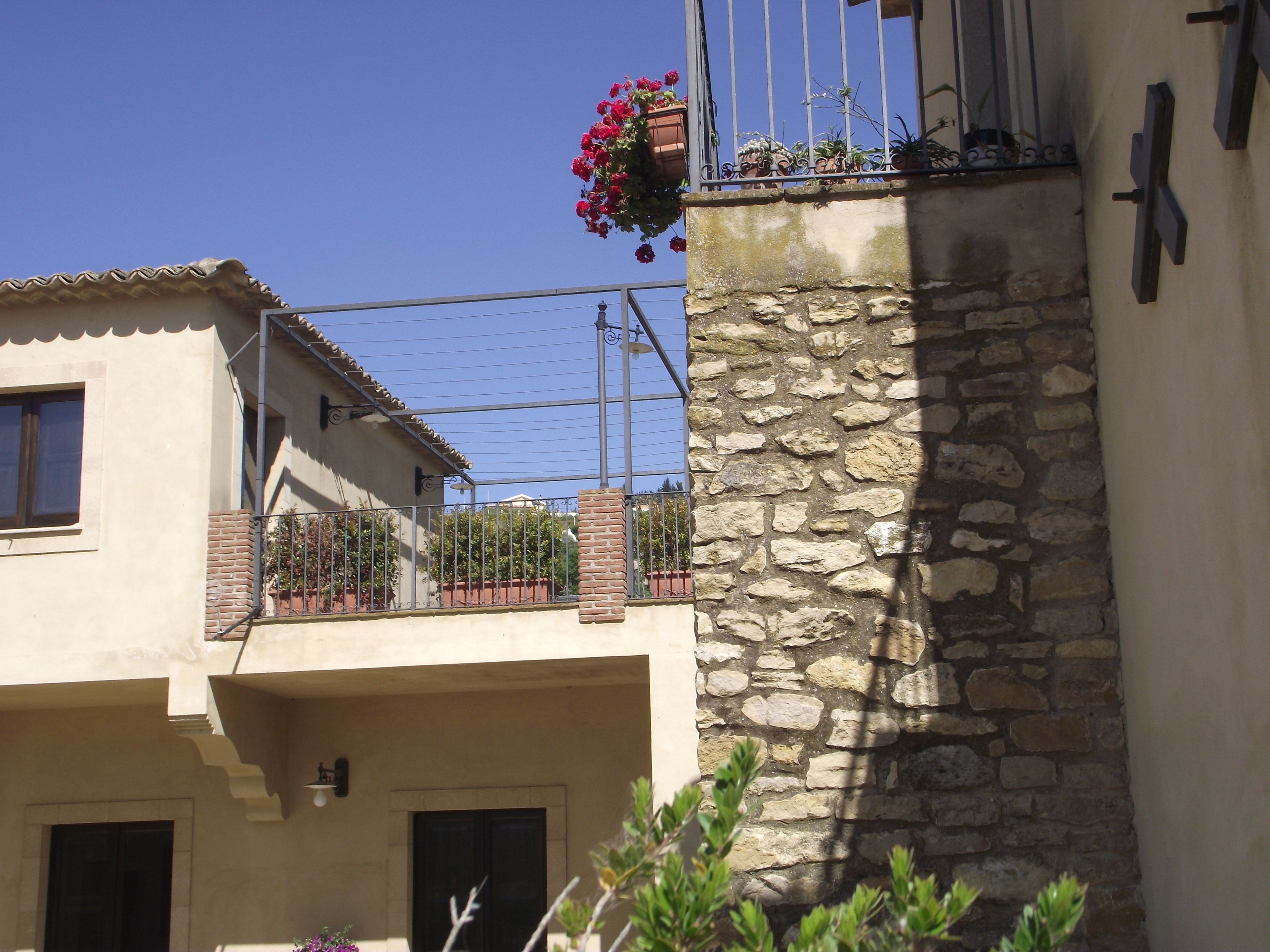 A traditional building with a stone wall and a balcony with potted plants.