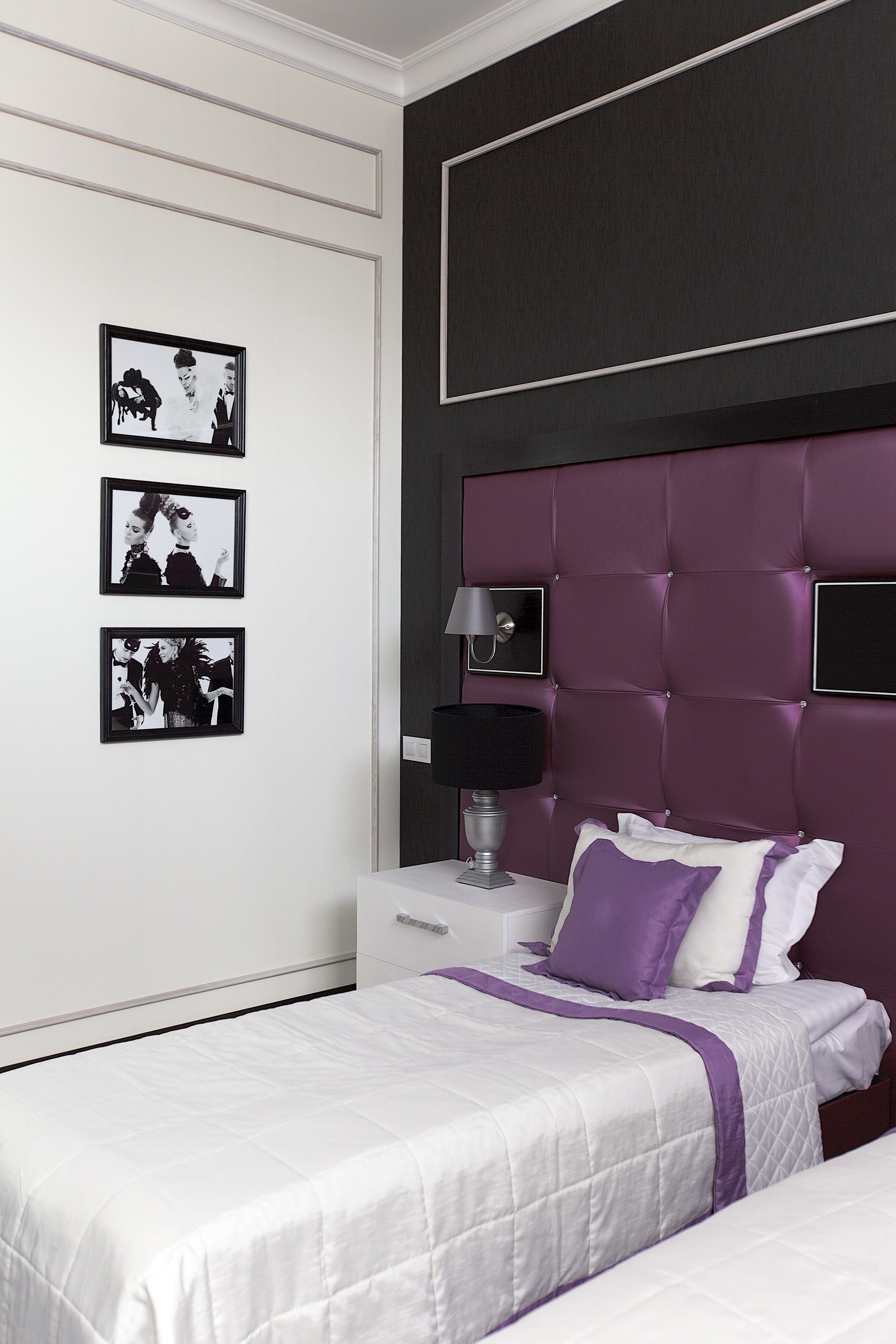 A bedroom with a white bed, a purple headboard, and three black-and-white framed pictures on the wall.