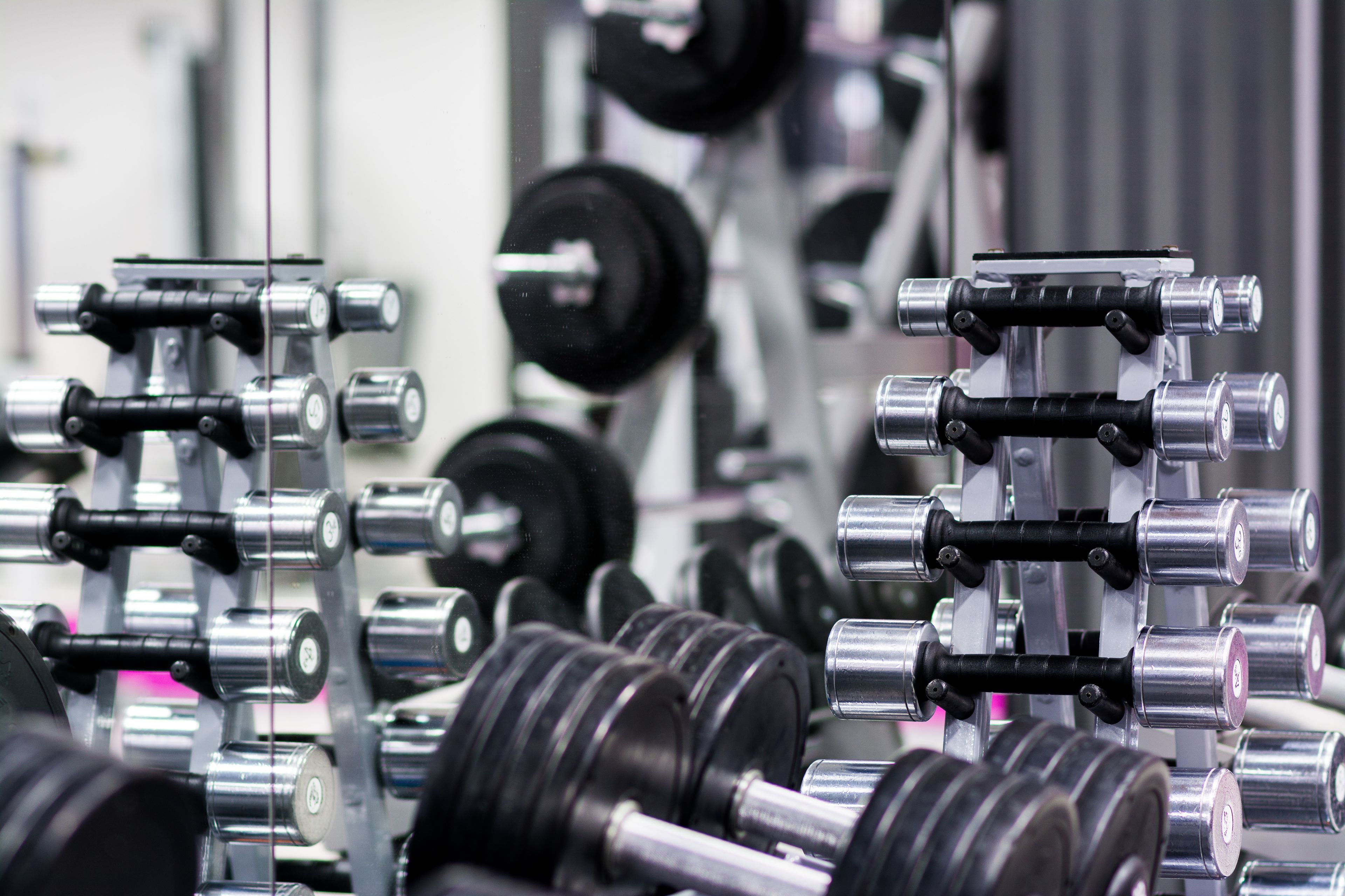 A gym with various weightlifting equipment, including dumbbells and barbells.