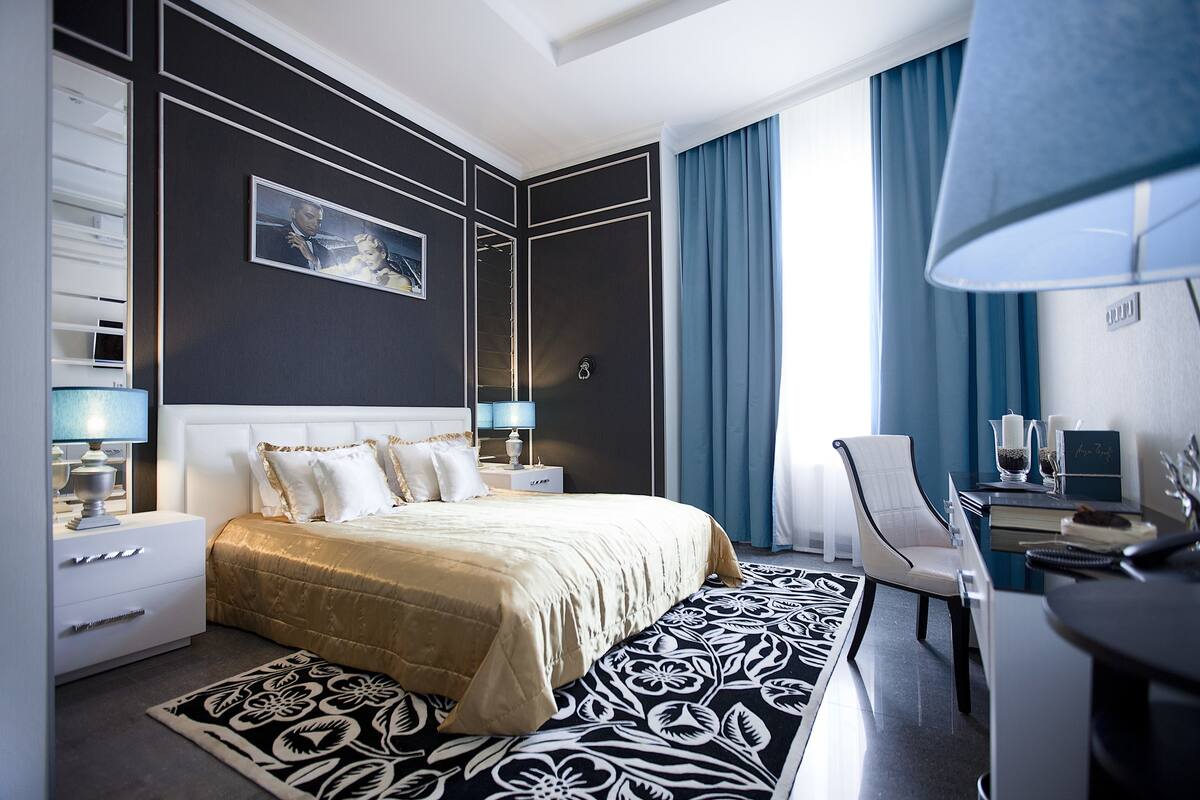 Una habitación de hotel moderna con una cama grande, un escritorio, una silla y una lámpara de escritorio.