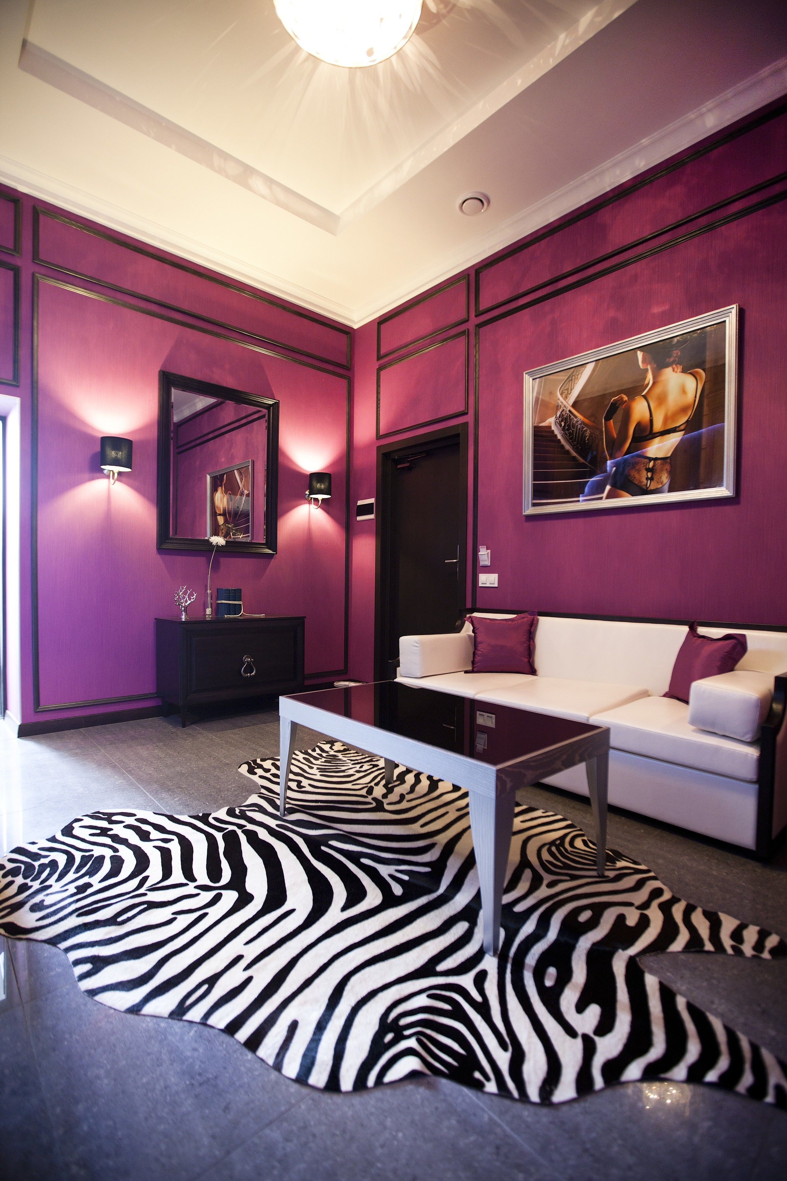A modern living room with a zebra-patterned rug, a white sofa, and a black cabinet.