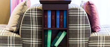 A bookshelf with books on a plaid sofa.