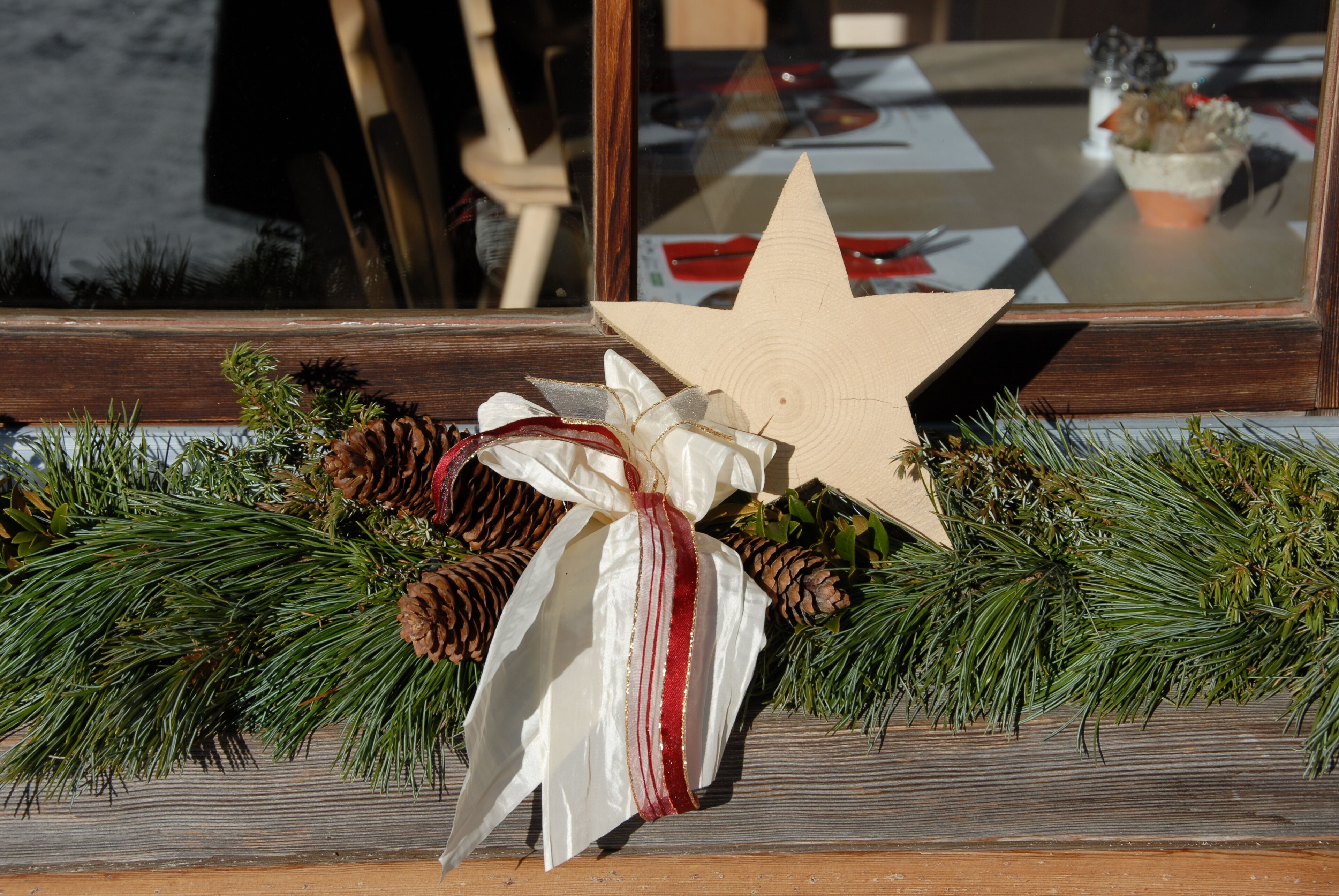 A wooden star decoration with pine branches and a plush toy.