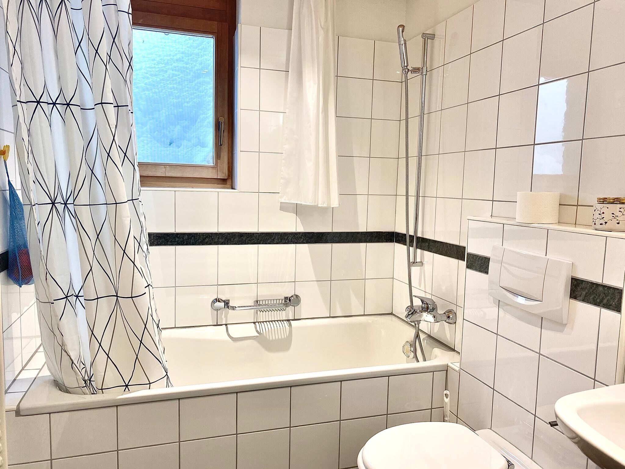 Een badkamer met een bad, een toilet en een raam.