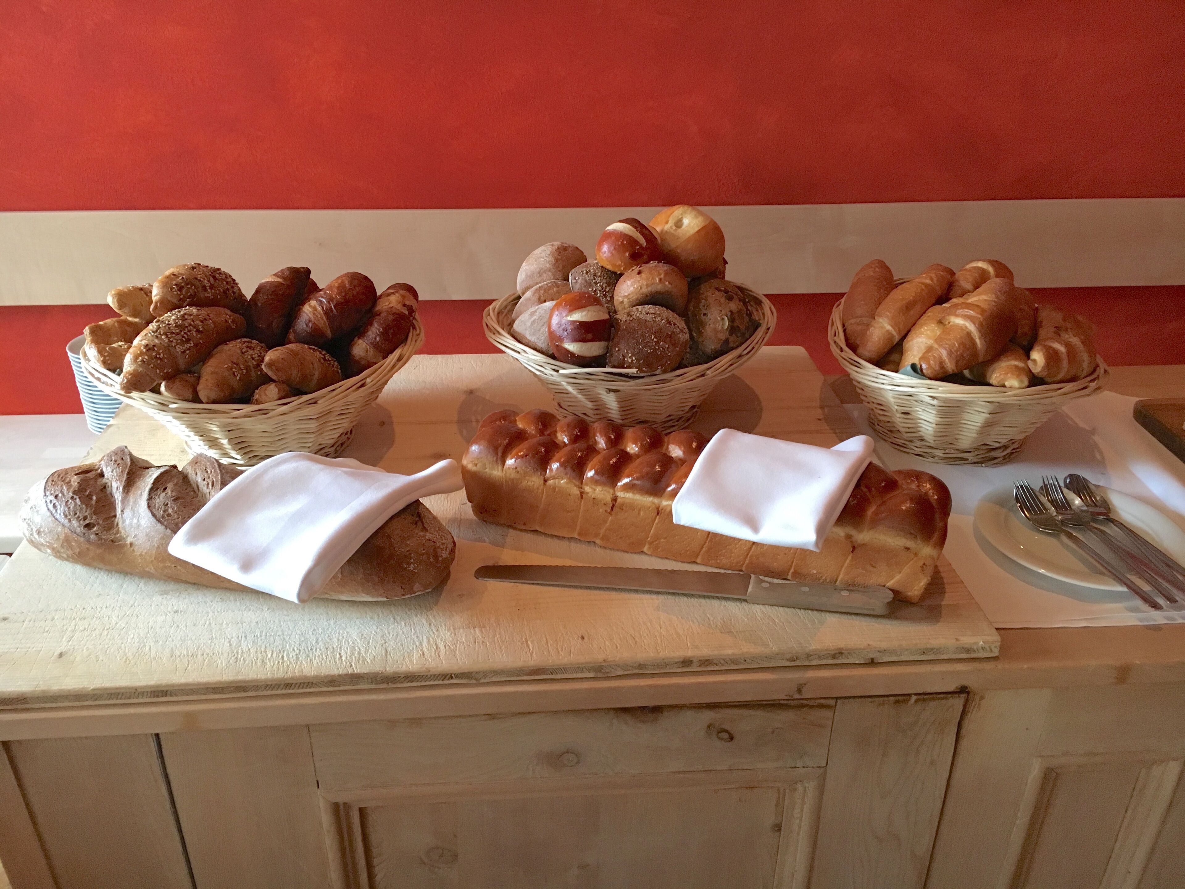 A display of various breads and pastries on a wooden counter with baskets.