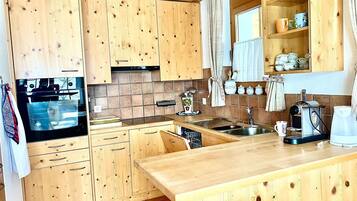 A kitchen with wooden cabinets, a built-in oven, a coffee maker, and a sink.